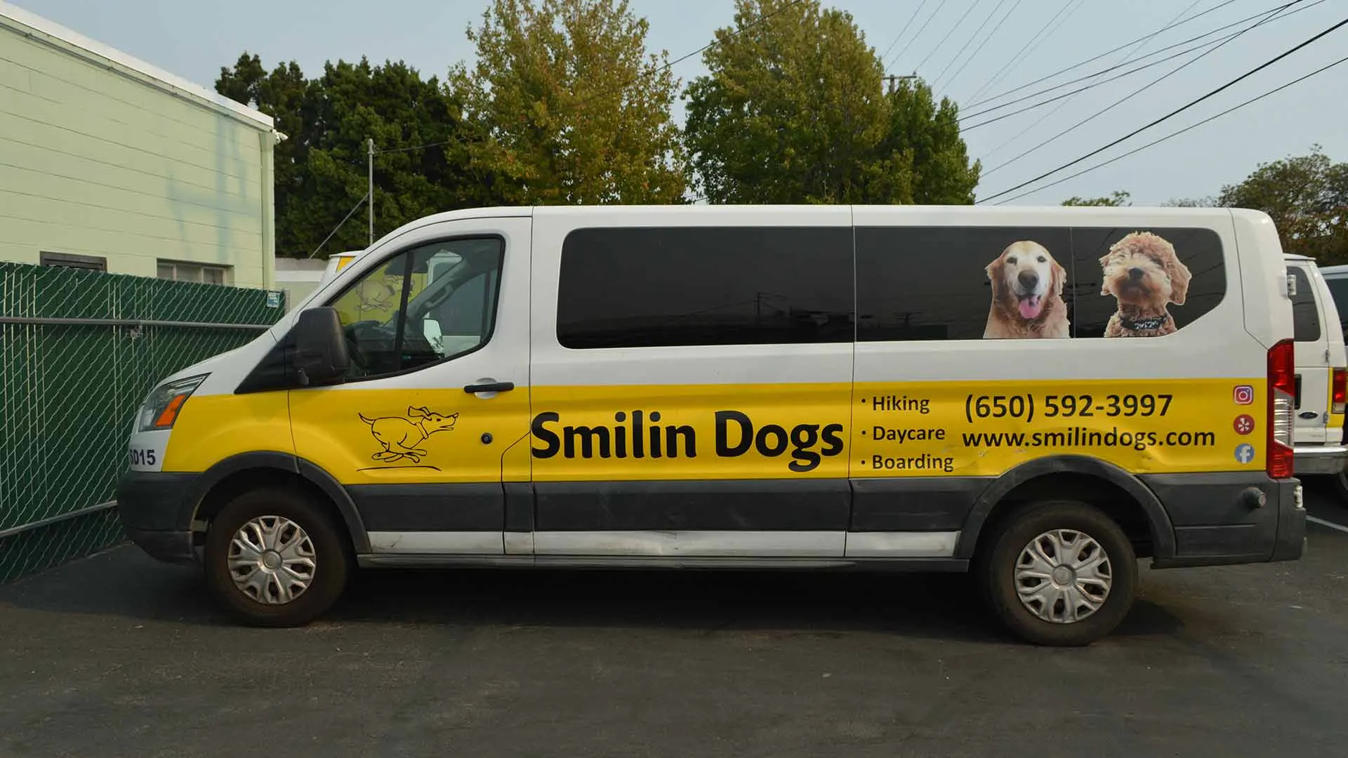 van White and yellow Smilin Dogs van with hiking, daycare and boarding text and phone (650) 592-3997